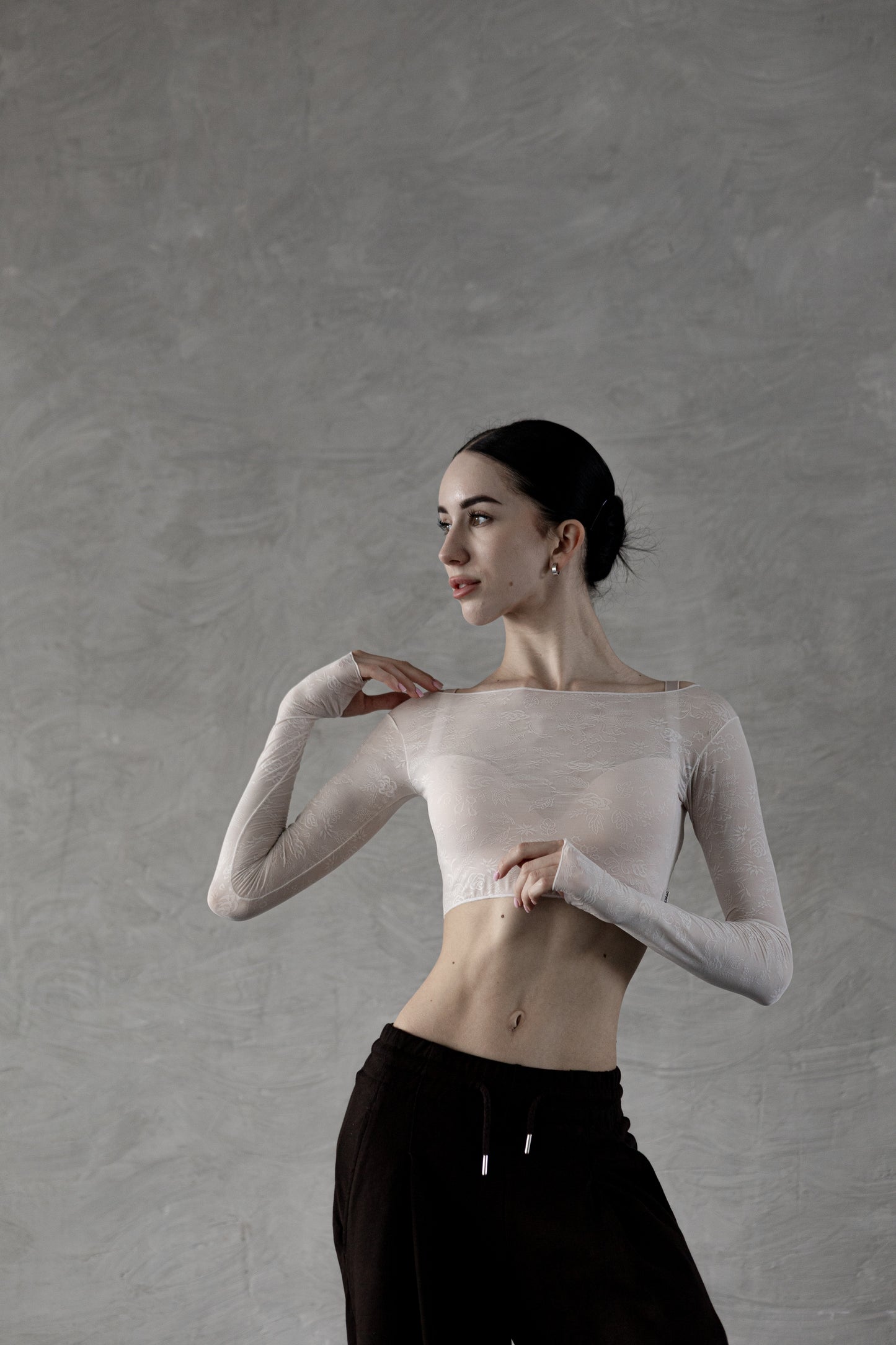 Dancer wearing a Dancelab top and black pants against a gray background