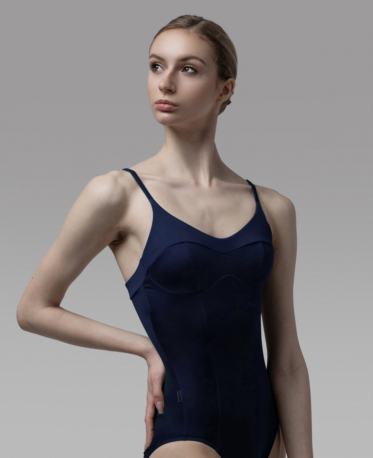 Woman wearing a navy blue bodysuit against a gray background