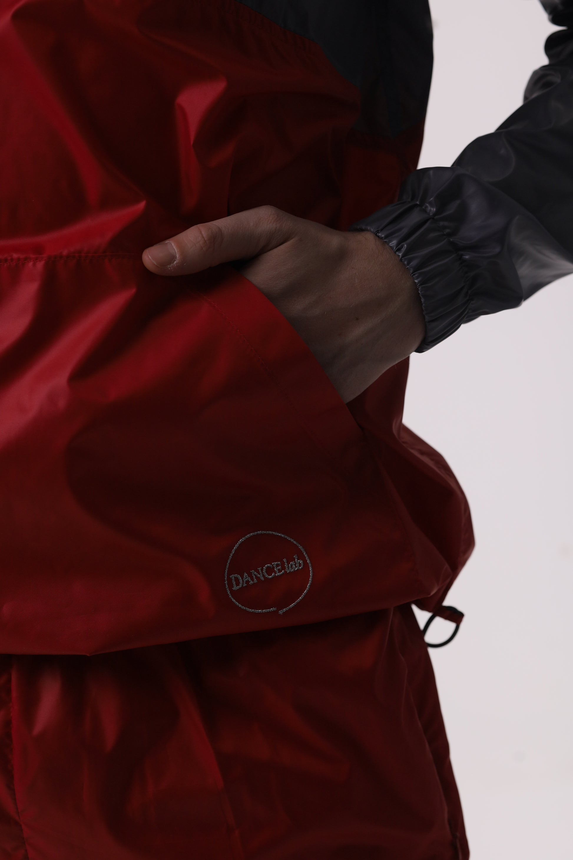 Dancelab red jacket with a brand logo held by a person against a neutral background