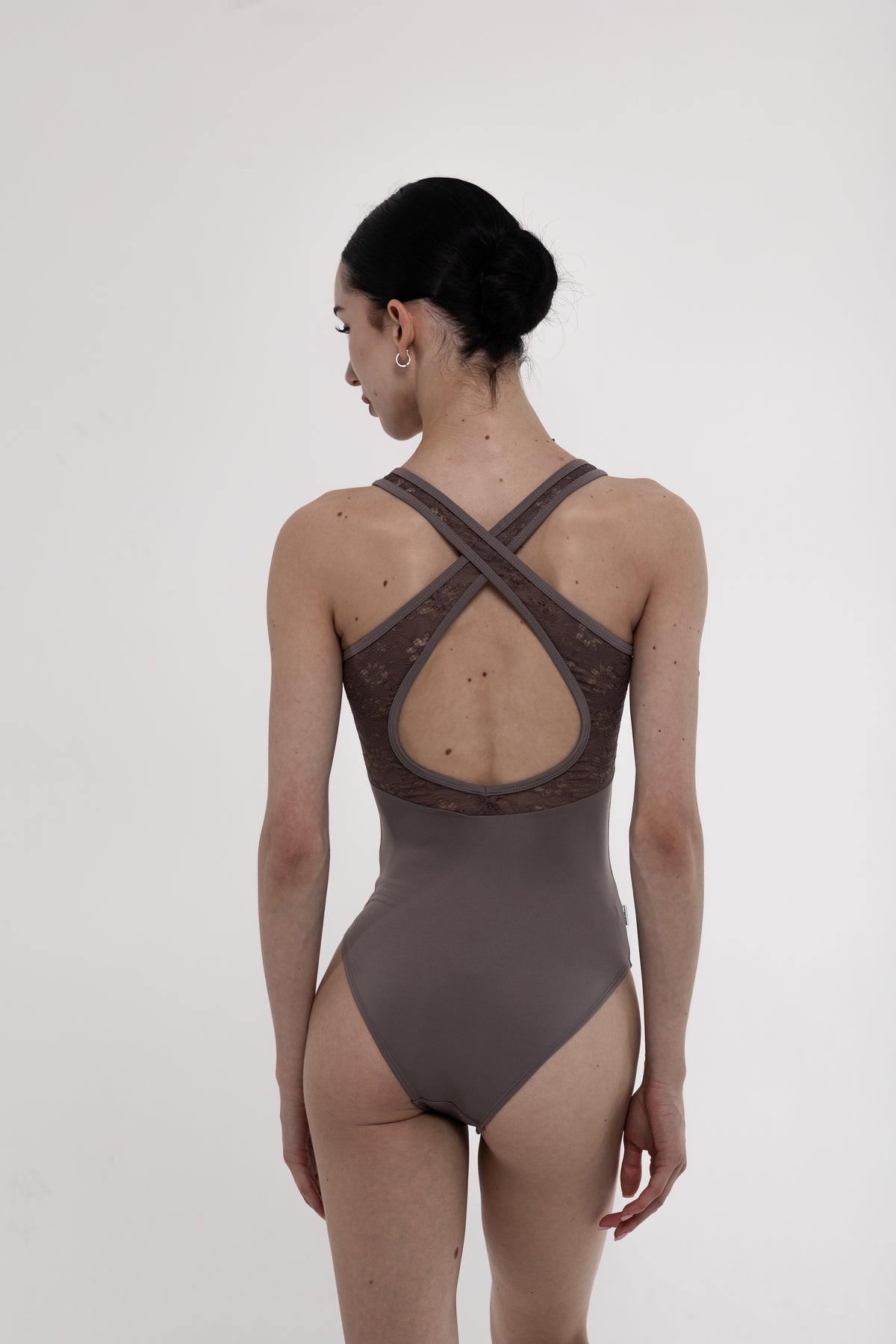 Ballerina wearing a brown ballet leotard with open back on a white background
