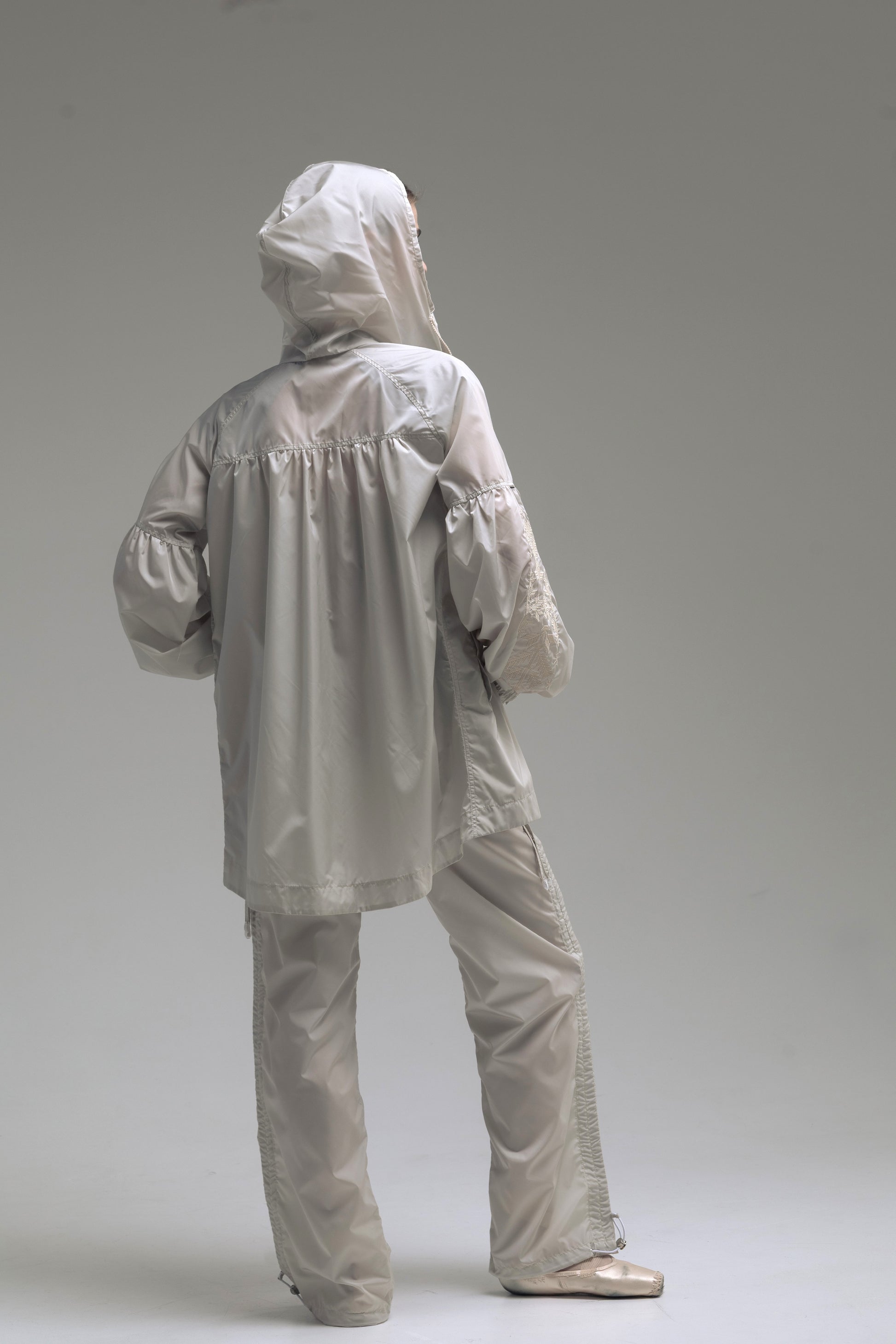 Ballerina wearing Embroidered suit Dancelab ivory color. A stylish suit with a hood and a logo on the sleeve.