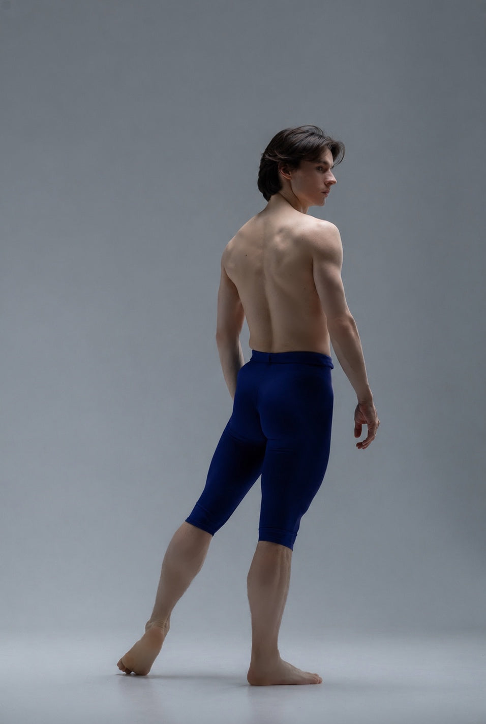 Ballet dancer in short blue tights on a gray background