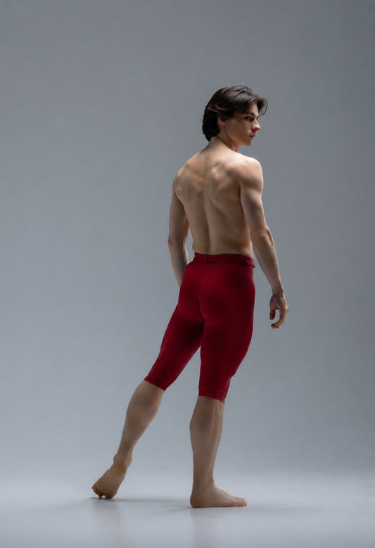 Ballet dancer wearing red short ballet tights on a gray background