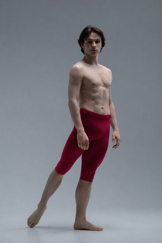 Ballet dancer wearing short red tights against a gray background