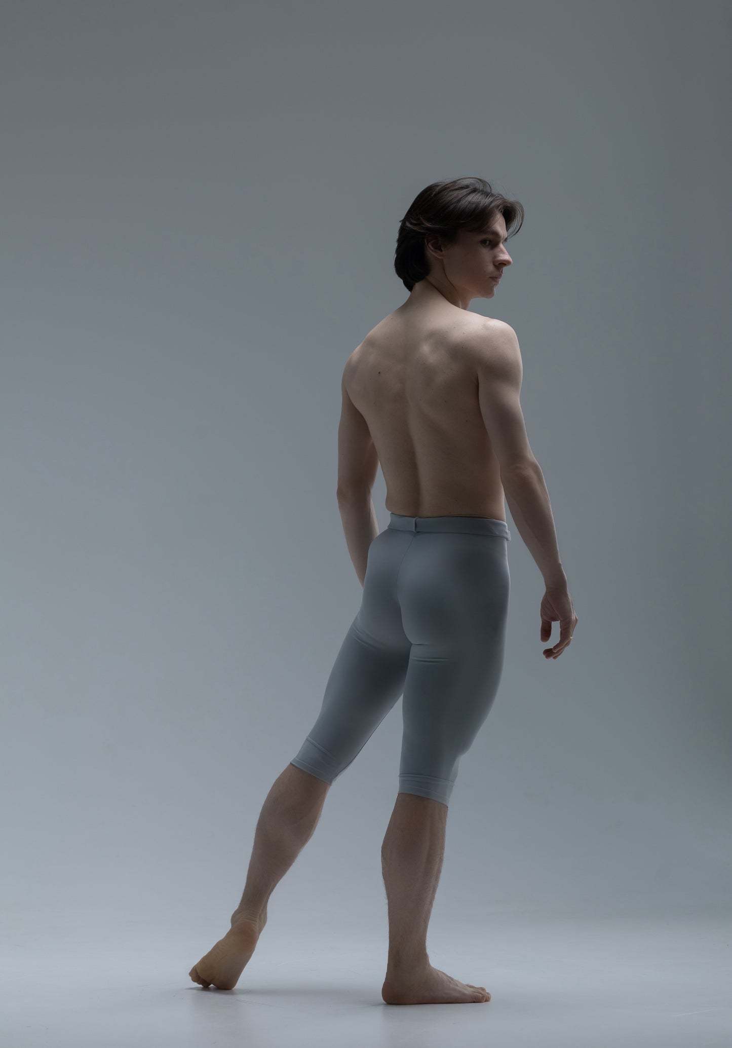 Man wearing grey short ballet tights against a grey background