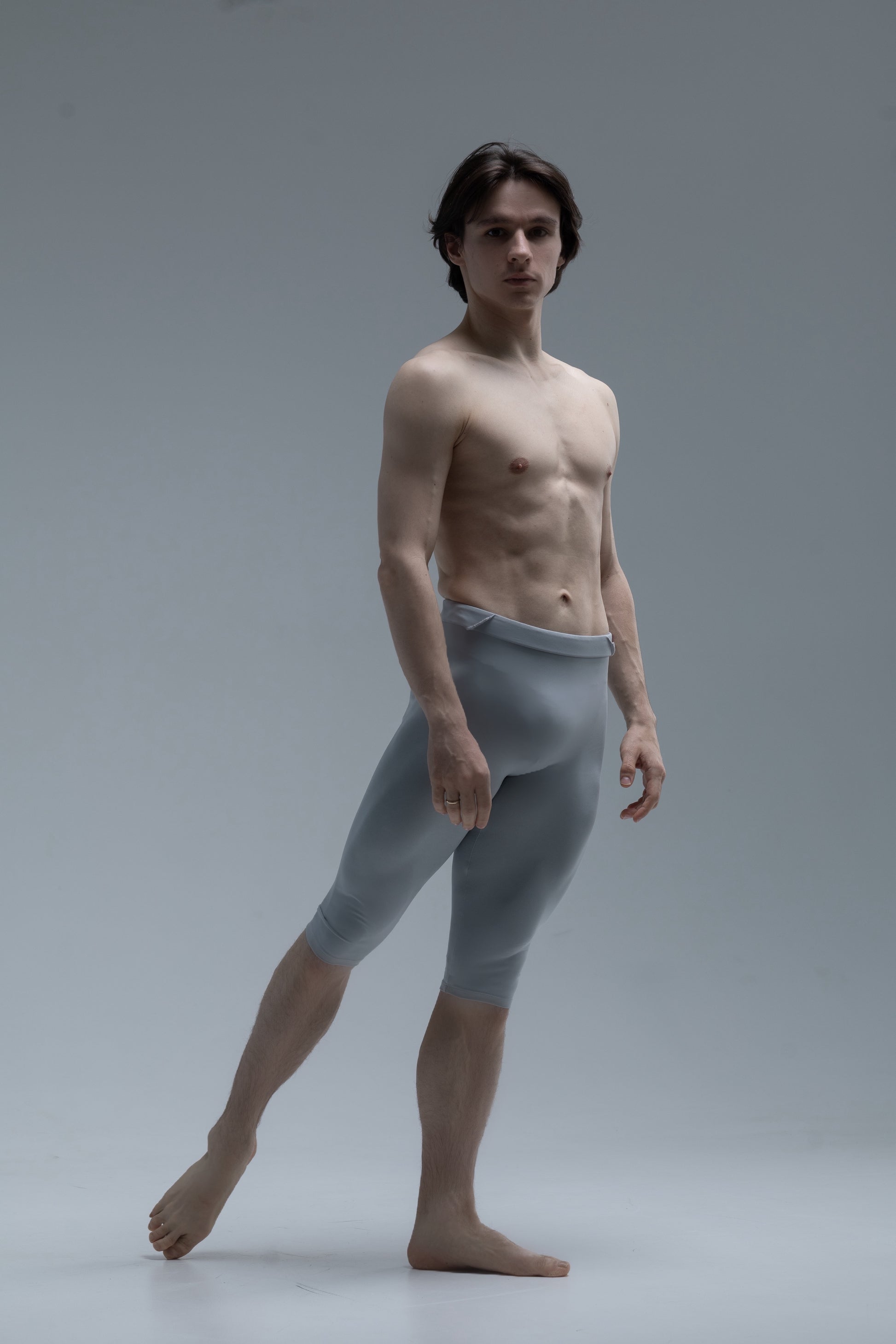 Man wearing light gray short ballet tights against a plain background