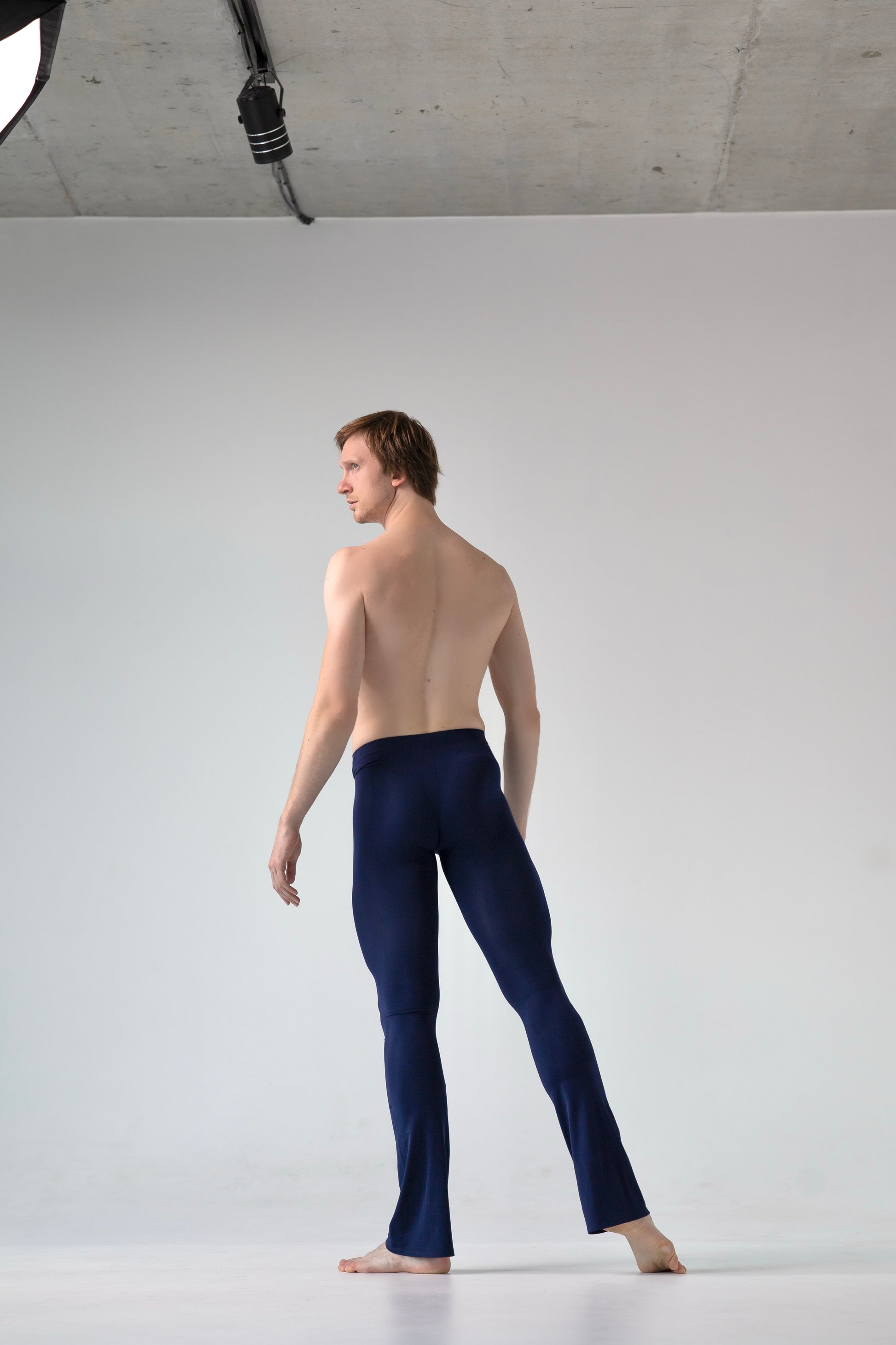 Man wearing navy blue pants standing against a white background