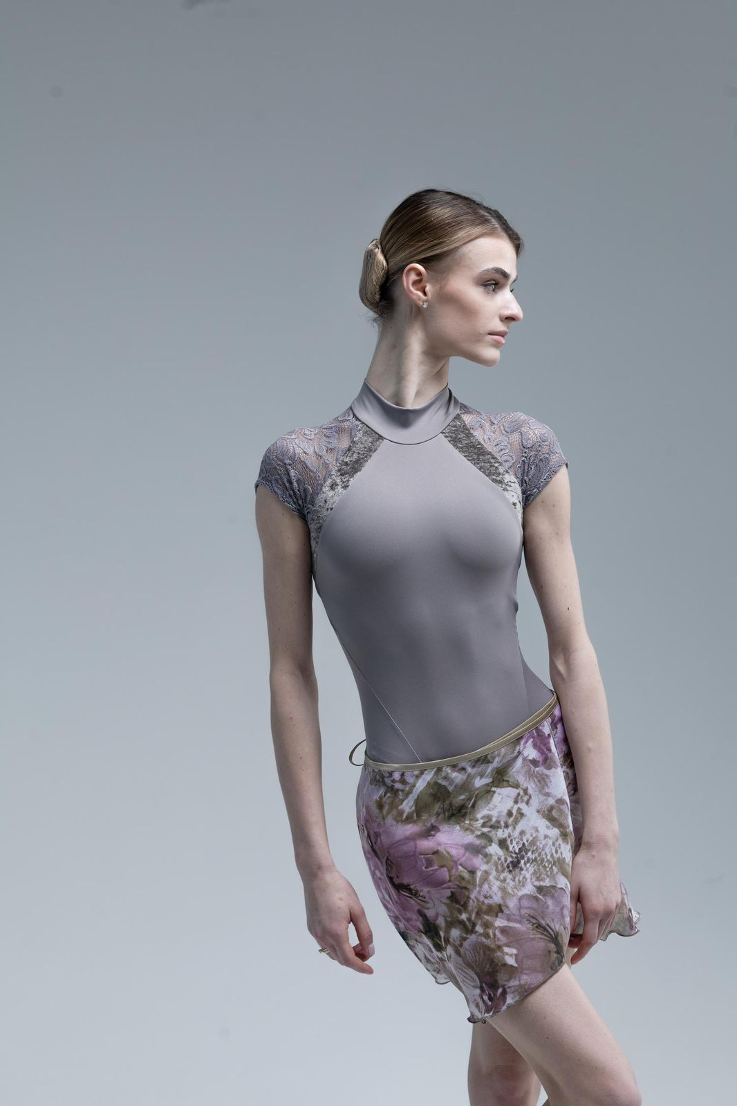 Ballerina wearing a gray leotard with lace sleeves and skirt lotos color