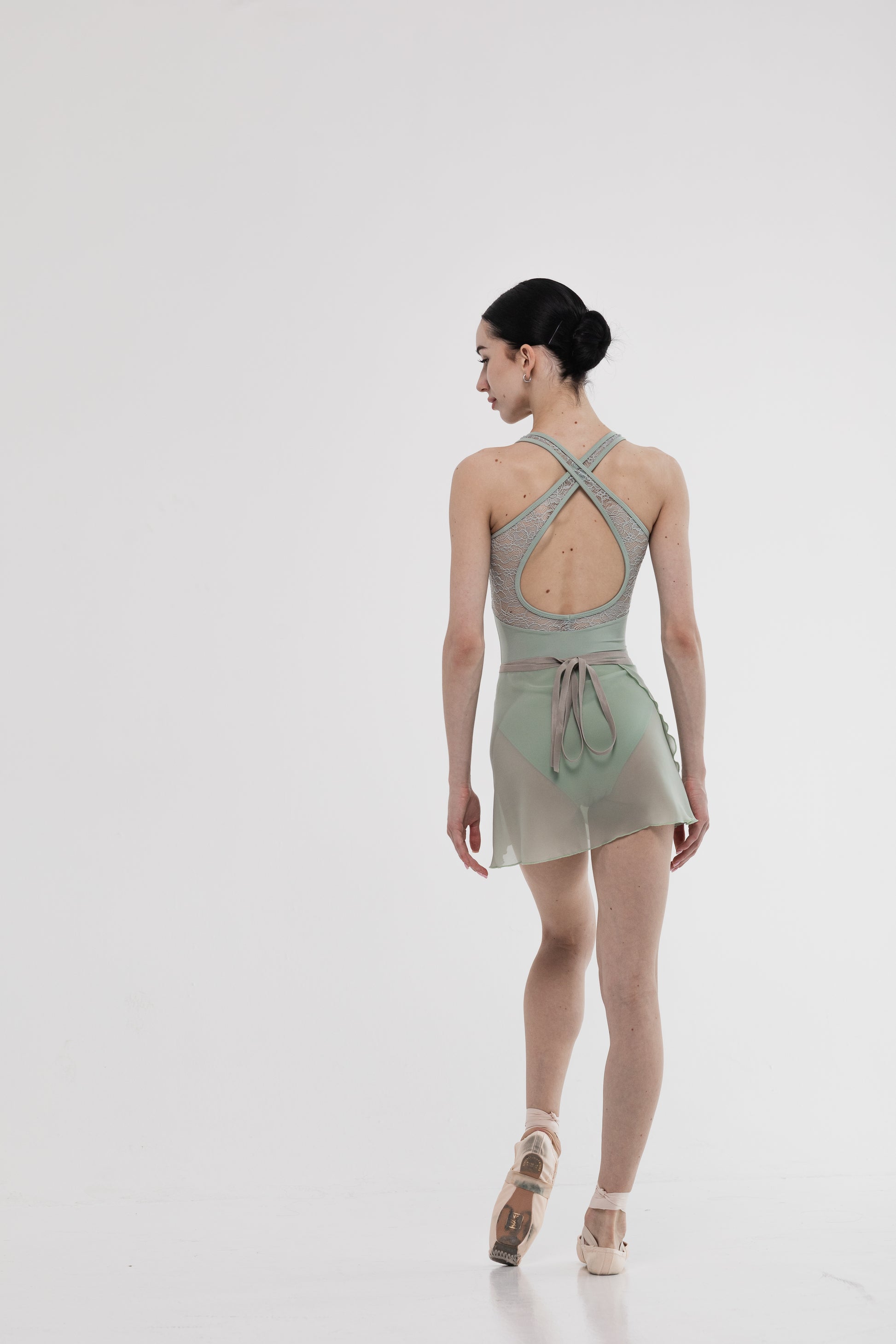 Girl wearing a light green skirt and leotard with open back