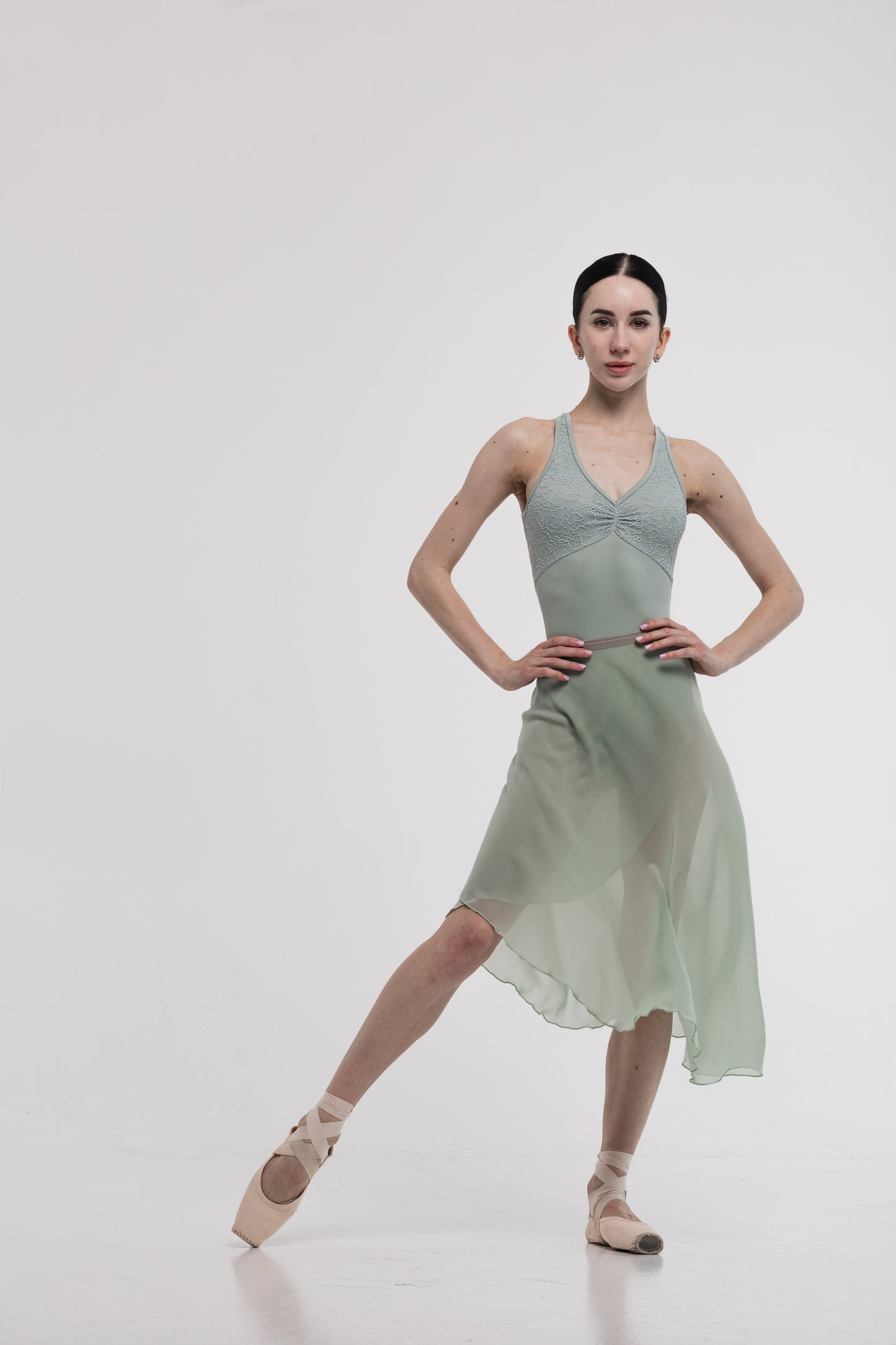 Ballerina in a pistachio skirt and leotard with lace on a white background