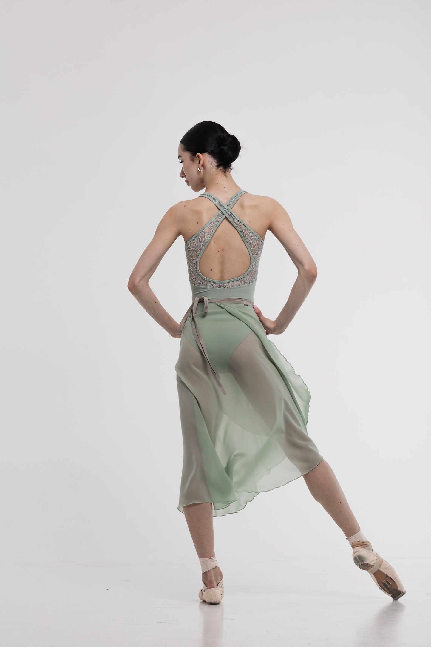 Dancer in a pistachio skirt with a Fleur leotard with lace on a white background